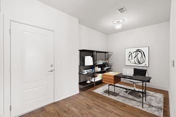 A room with a desk, laptop, and bookshelf.